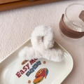 Dettaglio della pinza per capelli in peluche color panna su vassoio in ceramica elegante - Bianco