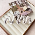 Detail view of wavy cream hair claw clip with black ink patterns in a jewelry box - White