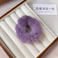 Macro view of a soft purple plush hair tie resting in a wooden jewelry storage box - Purple