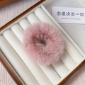 Detailed close-up of a pink plush faux fur hair scrunchie in a white jewelry box - Lotus root pink