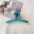 Macro view of a large cyan claw clip with black abstract ink patterns on white wool - Medium-Lake Blue