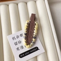 Detail of coffee brown hair clip featuring yellow and white knitted wool edge design - Brown