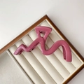 Macro detail of dusky pink wavy hair claw clip on white velvet jewelry display - Glossy Rose Pink