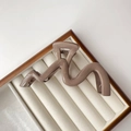 Detailed macro view of a mocha brown wavy hair claw clip resting on a velvet jewelry box - Glossy Milk Tea