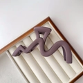 Close-up of matte purple wave claw clip on white velvet display for high hair volume - Matte Purple