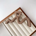 Close-up of matte brown wavy hair claw clip with strong metal spring in a display box - Frosted / Matte Milk Tea