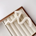 Detail of a matte cream-colored wavy hair claw clip resting on a velvet jewelry box - Frosted / Matte White