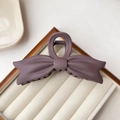 Macro detail of a large matte purple bow hair claw clip with elegant resin texture - Purple