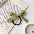 Detailansicht eines matcha-grünen Häkelbogen-Haargummis auf einer offenen Buchseite - Grün