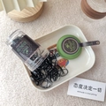 Detail of black rubber hair bands in a transparent jar on a white ceramic tray - Matcha Green