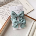 Close-up of light blue satin ribbon bow hair clips on jewelry display card - Mint Green