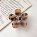 Detail of leopard print flower claw clip with rhinestones on an open book background - Amber With Rhinestones