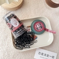 Macro shot of black elastic hair ties in a clear jar with vintage floral label and tray - Grey Green