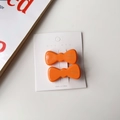 Gros plan détaillé de deux barrettes à cheveux en acétate orange sur carte de marque - Orange
