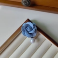 Detalle de broche de rosa de terciopelo azul con perla blanca en caja joyero - Azul