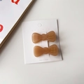 Vue détaillée de barrettes à cheveux nœuds en acétate ambré sur carte de présentation - Café au Lait