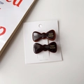 Gros plan sur des barrettes nœuds en écailles de tortue avec inscription dorée à la main - Chocolat