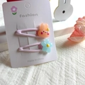 Close-up of cute resin rabbit and blue flower hair clips for girls on display card - Light Pink