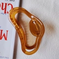 Macro shot of amber resin hair claw clip with golden metal spring on white background - Brown