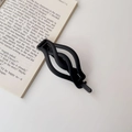 Elegant matte black twist hair clip for ponytail styling on an open book background - Matte Black