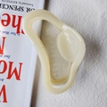 Macro detail of large cream jelly-colored claw clip with wavy cloud shape design - Beige