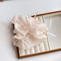 Détails de la texture d'un chouchou en organza champagne avec petits nœuds blancs en ruban - Blanc Cassé
