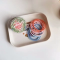 Detail of colorful high-elastic hair ties in a clear round box with floral design - Orange and Blue Colors