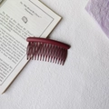 Macro shot of matte burgundy hair comb with multi-tooth curved design on textured book - Round Head Afro Comb / Burgundy