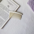 Cream-colored wave tooth hair comb accessory on an open book with soft lighting - Round Head Afro Comb / Ivory