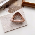 Macro view of coffee brown triangular hair claw clip with glossy finish and metal spring - Geometric Khaki