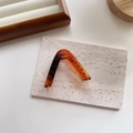Detail of a large triangular amber claw clip with tortoiseshell texture on stone surface - V-shape Amber