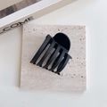 Detalle de pinza para el pelo grande en negro mate con diseño multidentado sobre piedra - Negro