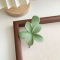Détail d'une pince à cheveux fleur vert sauge mat sur un fond de cadre vintage - Vert