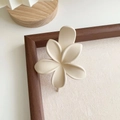 Détail de la pince à cheveux fleur crème avec texture mate sur décor en bois - Blanc