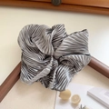 Detail of silver-grey pleated satin scrunchie showing glossy texture and elegant folds - Gray