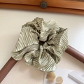Macro detail of large light olive green satin scrunchie with pleated metallic sheen texture - Fruit Green