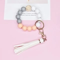 Beaded wristlet keychain with white tassel and silicone beads on a soft pink background - White