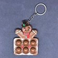 Nahaufnahme eines Lebkuchenmann Pop-it Schlüsselanhängers mit braunen Silikonblasen und Dekor - Weihnachtsfigur