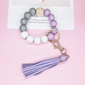Detail of wooden and silicone beaded wristlet keychain with purple leather tassel and gold ring - Purple