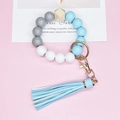 Detail of wooden bead keychain bracelet with blue tassel and gold metal hardware - Blue