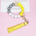 Detail of wooden and yellow silicone bead keychain bracelet with long tassel and gold ring - Yellow