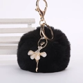 Détail d'un porte-clés pompon en fausse fourrure noire avec une danseuse étoile scintillante - Pompon de 8 cm / Noir