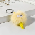 Detail view of a yellow plush monster keychain with a furry ball and ice cream cone base - Beige