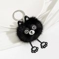 Close-up of black plush animal keychain with cute round eyes on a white silk background - Black