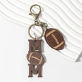 Creative wooden MOM keychain with American football charm and bronze hook on white surface - Rugby Football Style