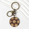 Macro view of vintage wooden keychain with honeycomb pattern and antique bronze metal clasp - Brown Soccer Wood
