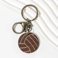Macro detail of wooden volleyball keychain with vintage bronze clasp on white texture - Brown Volleyball Wood
