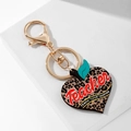 Primer plano del llavero con forma de manzana y estampado de leopardo sobre mármol - Manzana Corazón de Leopardo