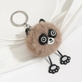 Close-up of a fluffy brown panda plush keychain with silver ring on white silk fabric - Brown