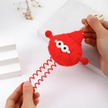 Detail eines roten Plüsch-Monster-Schlüsselanhängers mit Federbeinen und Strickmütze - Rot